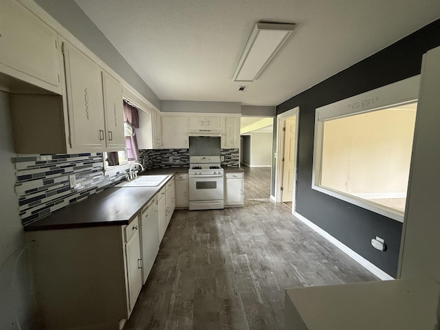  - kitchen featuring white appliances, backsplash, dark wood finished floors, under cabinet range hood, and white cabinets