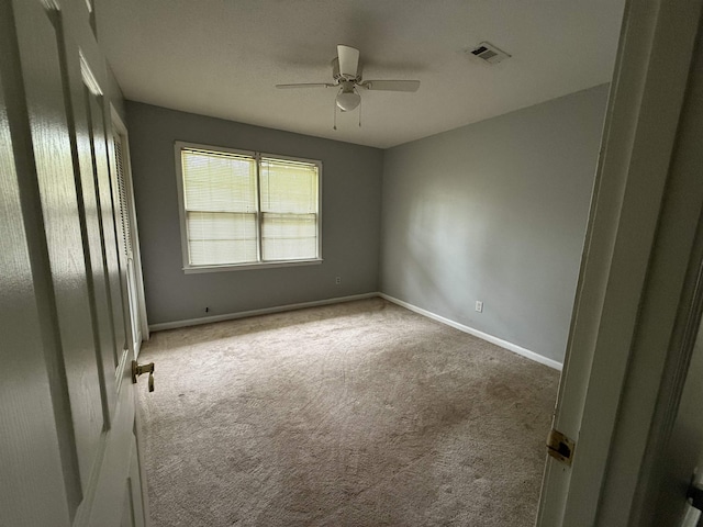  - carpeted spare room with a ceiling fan and baseboards