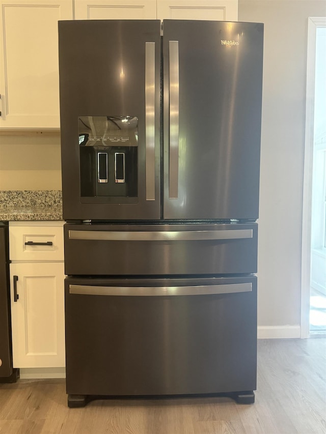 room details featuring white cabinetry, light stone counters, stainless steel refrigerator with ice dispenser, and light wood-type flooring