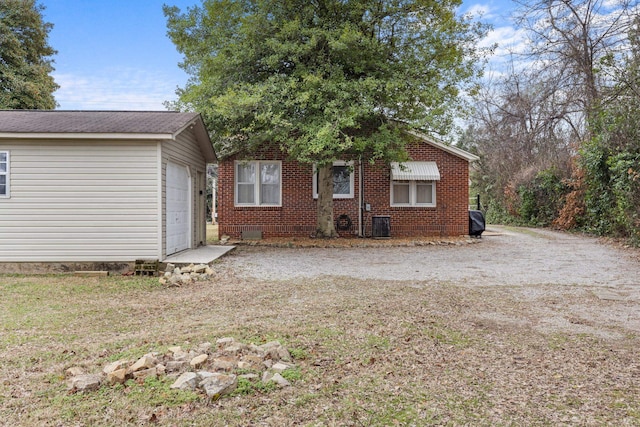 rear view of property featuring a garage and central AC