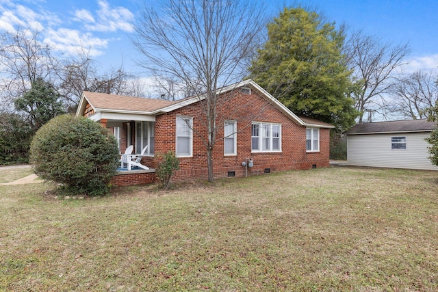 view of side of home with covered porch, an outbuilding, and a lawn