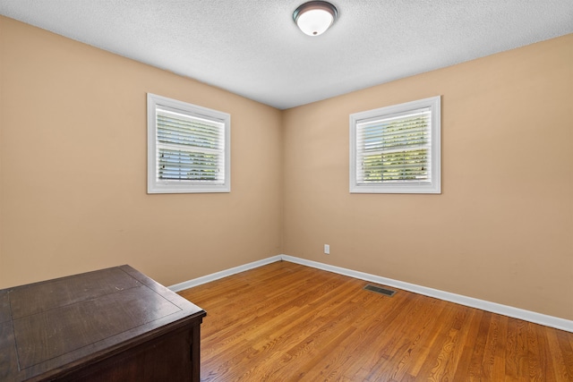  - empty room featuring baseboards, light wood-style flooring, and a textured ceiling