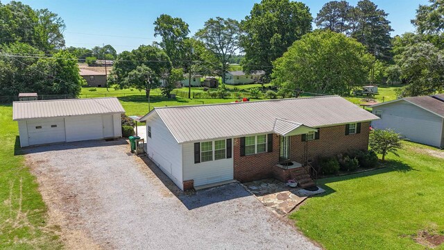  - ranch-style house featuring an outbuilding, a detached garage, a front yard, and metal roof