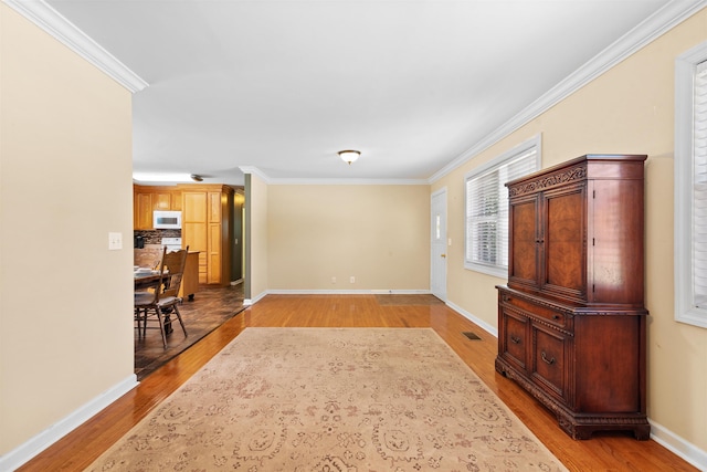  - unfurnished living room featuring light wood-type flooring, crown molding, and baseboards