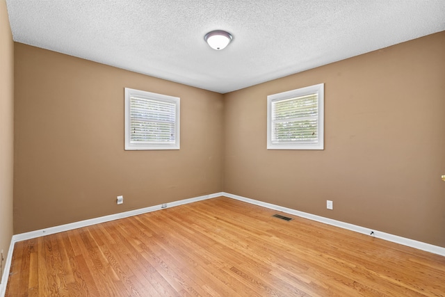 - empty room with light wood-style flooring, baseboards, and a textured ceiling