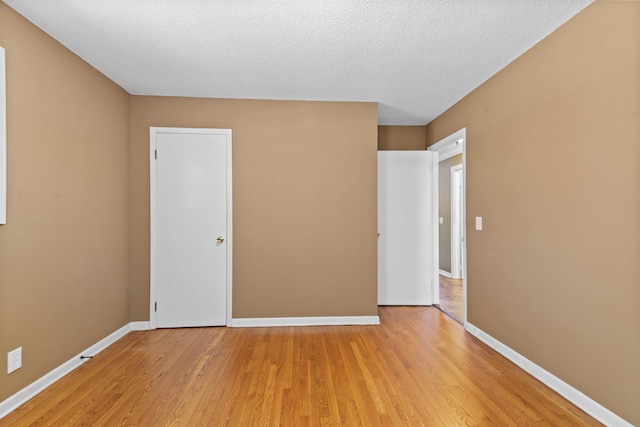 - unfurnished room with light wood-style flooring, baseboards, and a textured ceiling