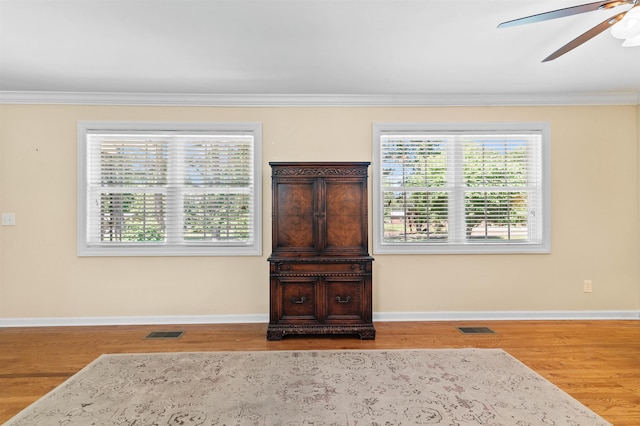 - detailed view of ceiling fan, ornamental molding, wood finished floors, and baseboards