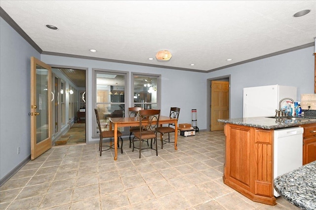 kitchen with sink, white appliances, ornamental molding, and dark stone countertops