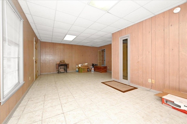 interior space featuring wooden walls and a drop ceiling