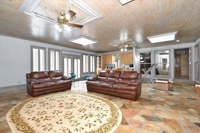 living room with a skylight, ceiling fan, wooden ceiling, and ornamental molding