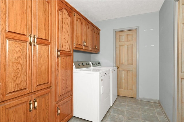 laundry room featuring cabinets, a textured ceiling, and washing machine and clothes dryer