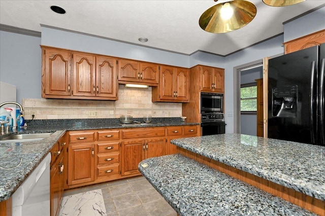 kitchen with decorative backsplash, stone countertops, black appliances, and sink