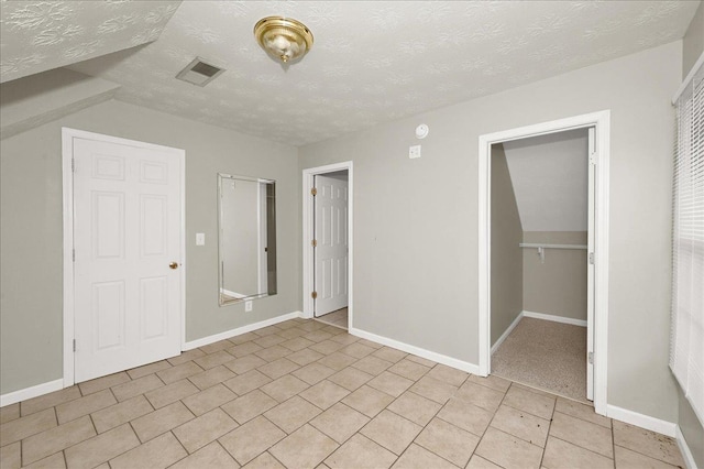 unfurnished bedroom with a textured ceiling, a closet, and light tile patterned flooring