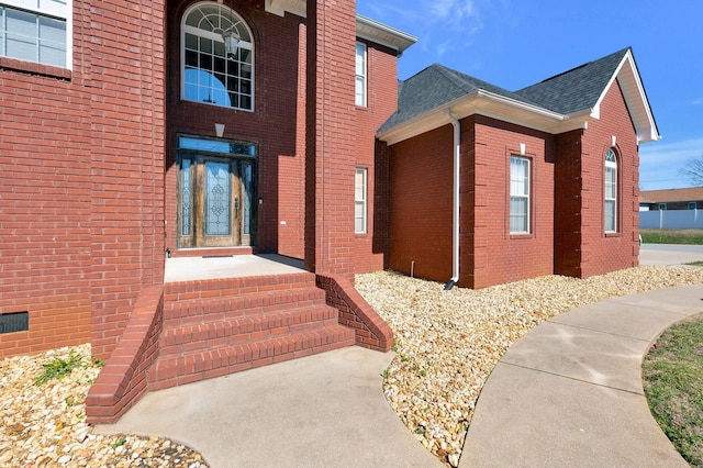 entrance to property with brick siding and roof with shingles