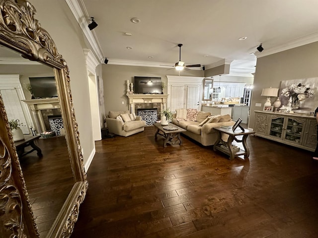 living room with dark wood-type flooring, ornamental molding, and ceiling fan