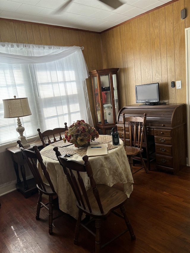 dining area with dark hardwood / wood-style floors and wood walls