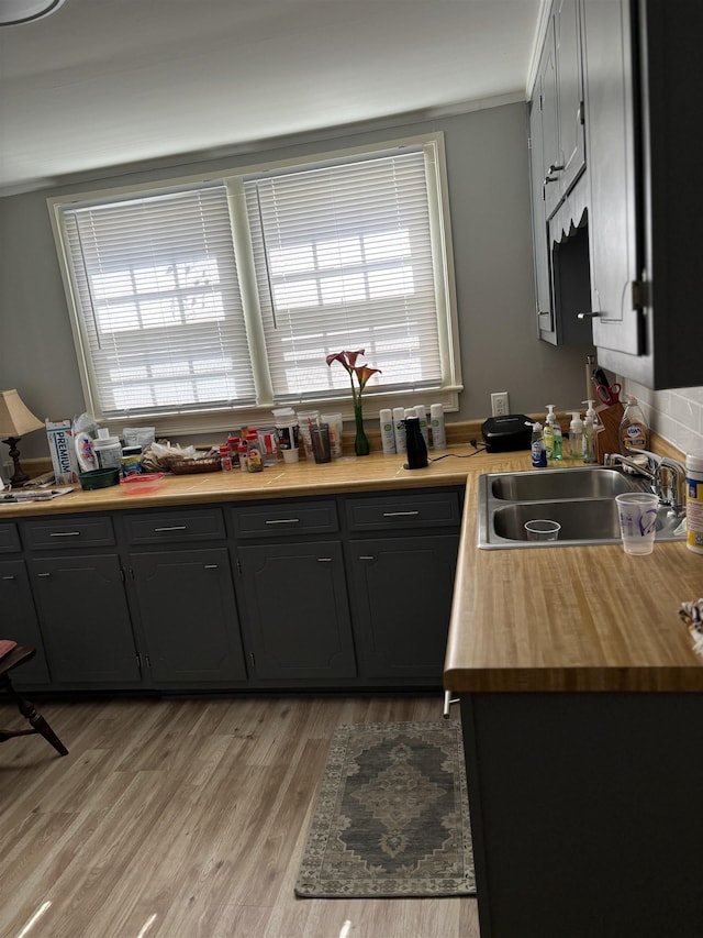 kitchen featuring light wood-type flooring, butcher block countertops, and sink