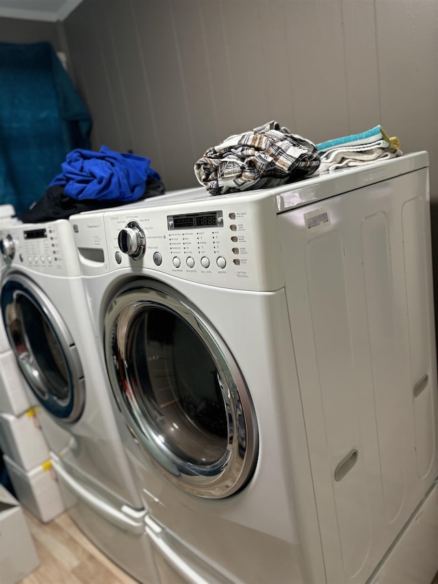 laundry room with wood-type flooring and washing machine and clothes dryer