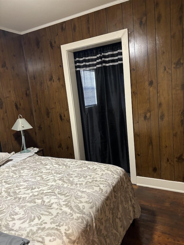 bedroom with dark hardwood / wood-style floors, wood walls, ornamental molding, and a closet