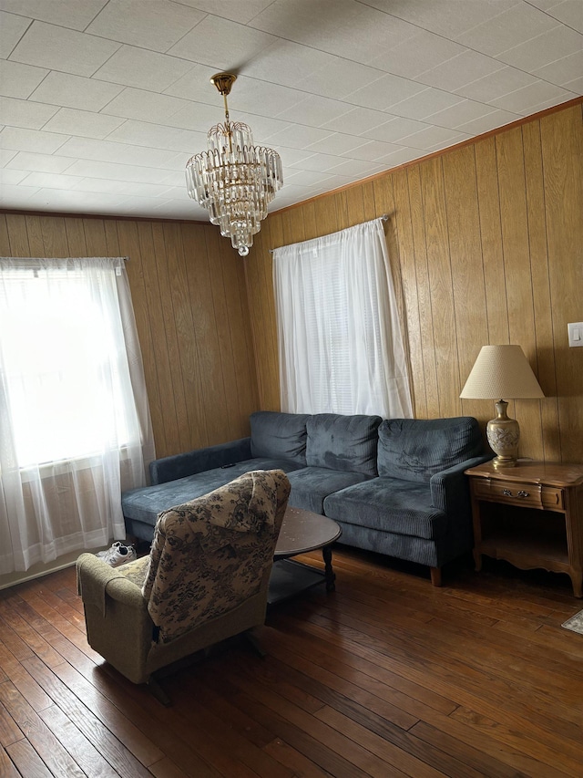 living room with wood walls, dark hardwood / wood-style floors, and an inviting chandelier