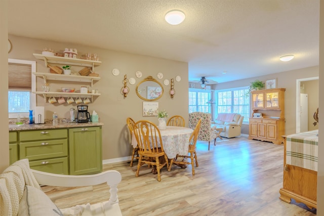 dining room with light wood-style floors, ceiling fan, a textured ceiling, and baseboards