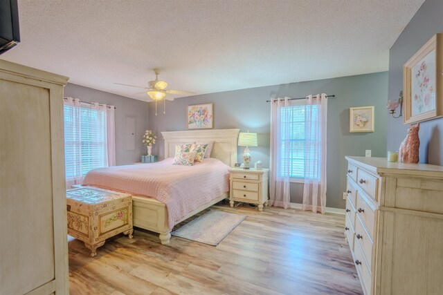 bedroom with light wood-style floors, ceiling fan, and a textured ceiling