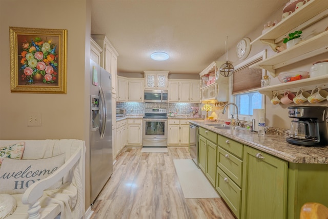 kitchen featuring open shelves, light wood-style flooring, appliances with stainless steel finishes, a sink, and green cabinetry