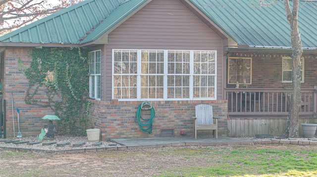 view of property exterior featuring metal roof and brick siding