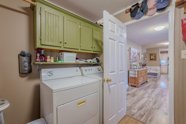 laundry area featuring washer and clothes dryer, light wood-type flooring, and cabinet space