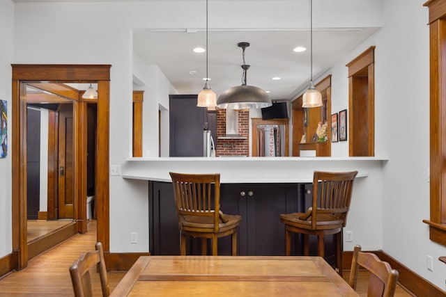 kitchen featuring light countertops, a breakfast bar area, a peninsula, and decorative light fixtures