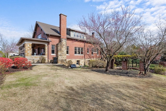 back of property with brick siding, fence, a chimney, and a lawn