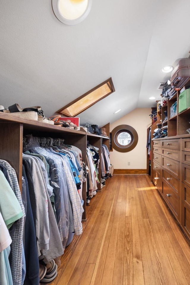 walk in closet with light wood-style floors, visible vents, and vaulted ceiling