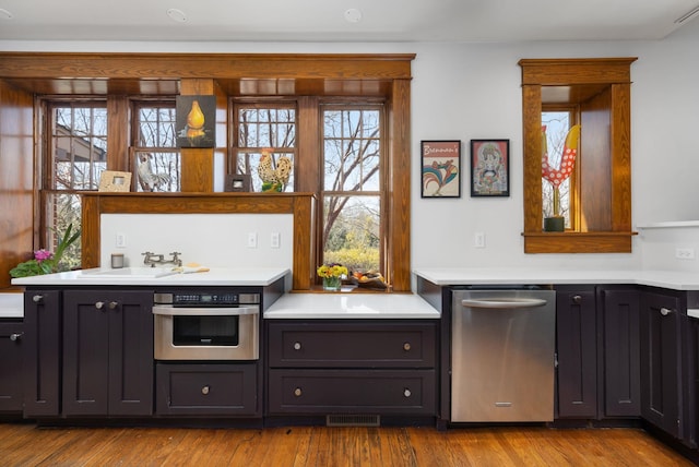 bar featuring visible vents, light wood finished floors, a sink, and stainless steel oven