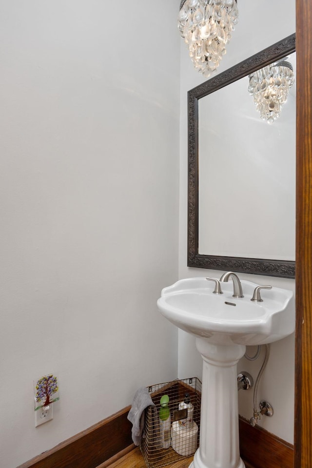 bathroom featuring baseboards, wood finished floors, and an inviting chandelier