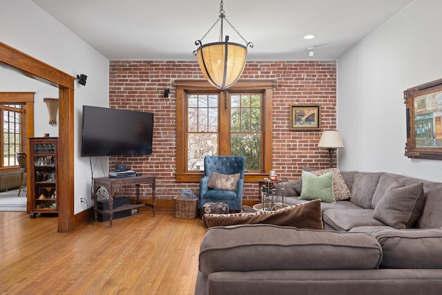 living room with brick wall, baseboards, radiator heating unit, and wood finished floors