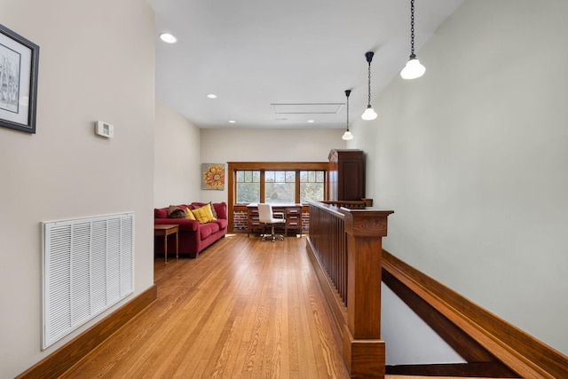 hall featuring light wood-style floors, recessed lighting, visible vents, and an upstairs landing