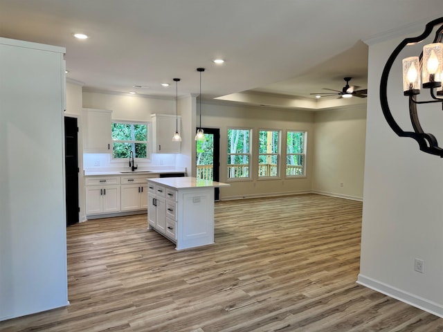  - kitchen with ceiling fan, white cabinets, open floor plan, a center island, and crown molding