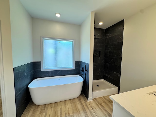  - full bath featuring vanity, wood finished floors, a freestanding bath, tile walls, and tiled shower