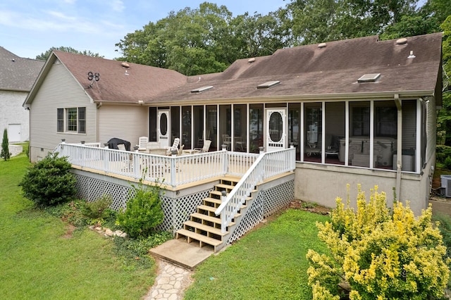 back of house featuring central AC, a sunroom, a yard, and a deck