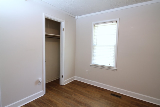 unfurnished bedroom featuring a textured ceiling, dark hardwood / wood-style floors, a closet, and crown molding