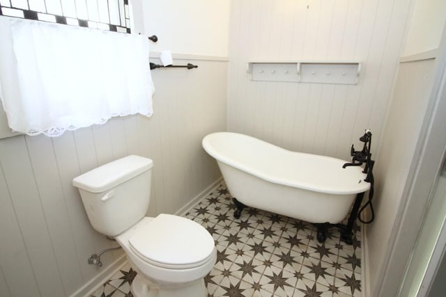 bathroom featuring toilet, a tub to relax in, and wooden walls