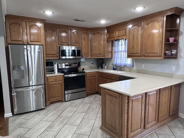 kitchen featuring appliances with stainless steel finishes, kitchen peninsula, and sink