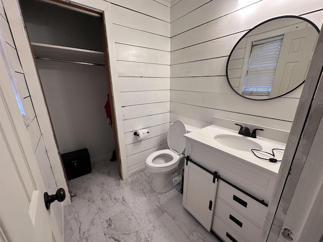 bathroom with vanity, toilet, and wood walls