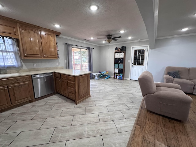 kitchen with sink, ornamental molding, a textured ceiling, stainless steel dishwasher, and kitchen peninsula