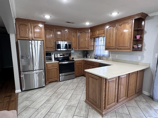 kitchen featuring appliances with stainless steel finishes, sink, a textured ceiling, and kitchen peninsula