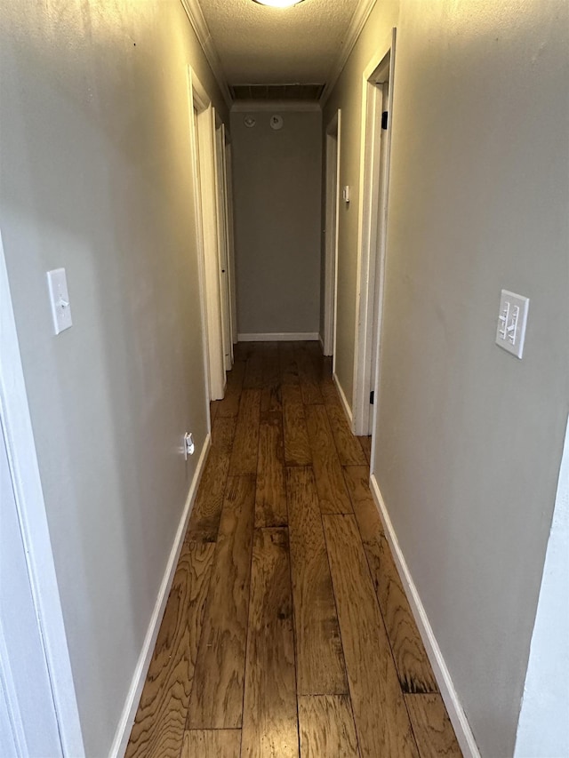 hallway featuring crown molding, wood-type flooring, and a textured ceiling