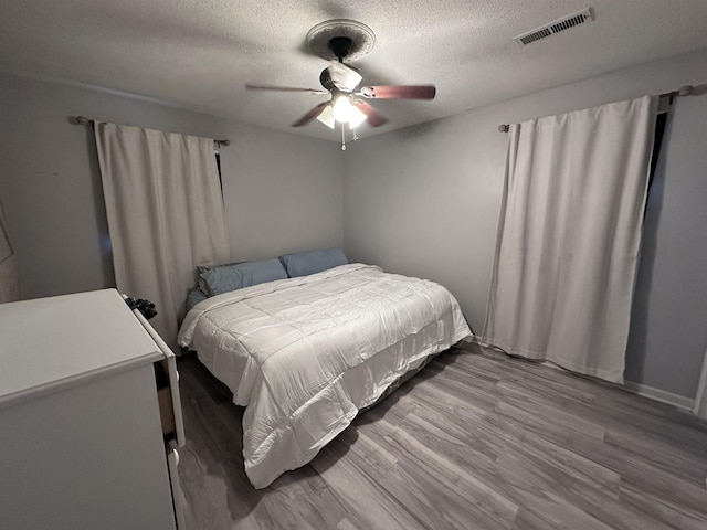 bedroom featuring ceiling fan, wood-type flooring, and a textured ceiling