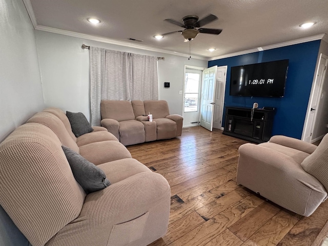 living room with crown molding, ceiling fan, and light wood-type flooring