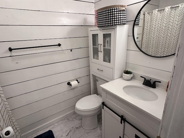 bathroom with vanity, wooden walls, and toilet