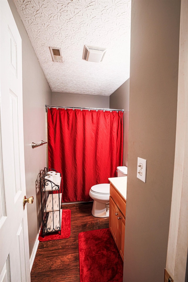 bathroom featuring a shower with curtain, vanity, a textured ceiling, hardwood / wood-style floors, and toilet